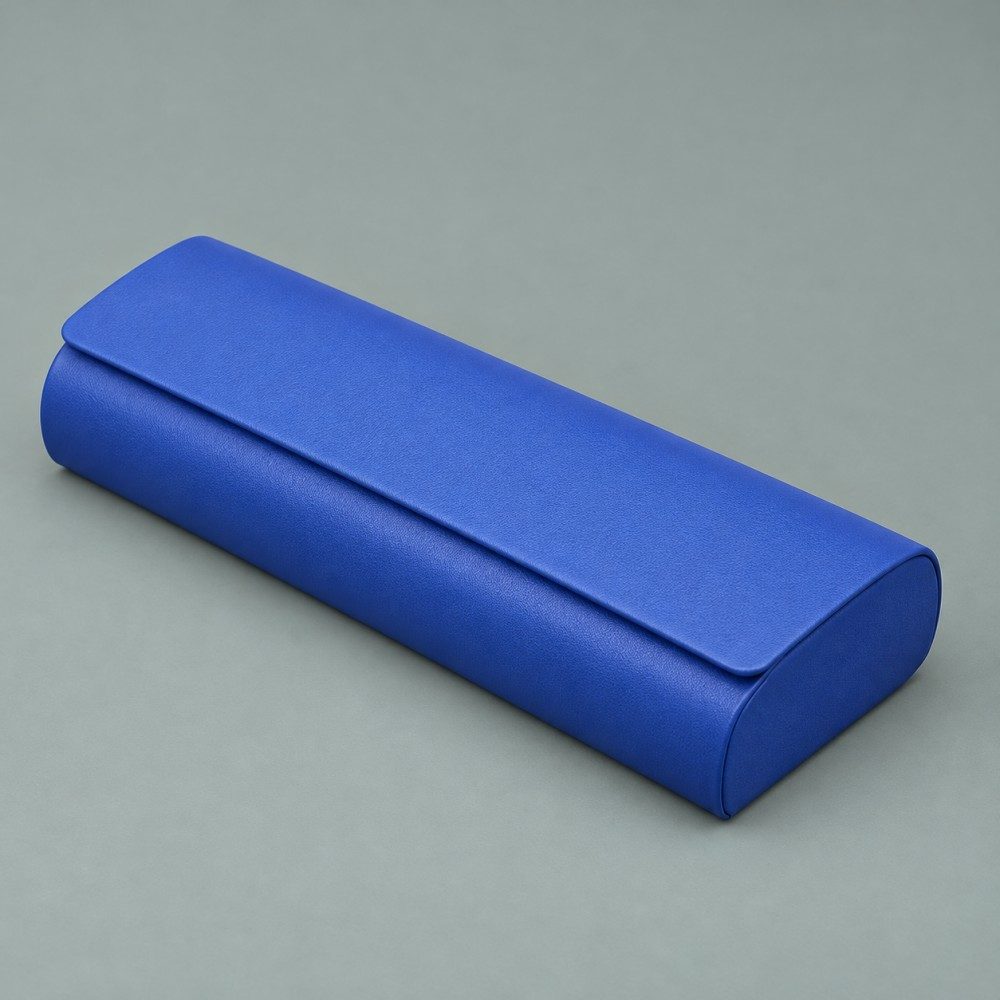 Royal blue magnetic eyeglass case with a rounded body and rectangular flap on a muted gray-green background.