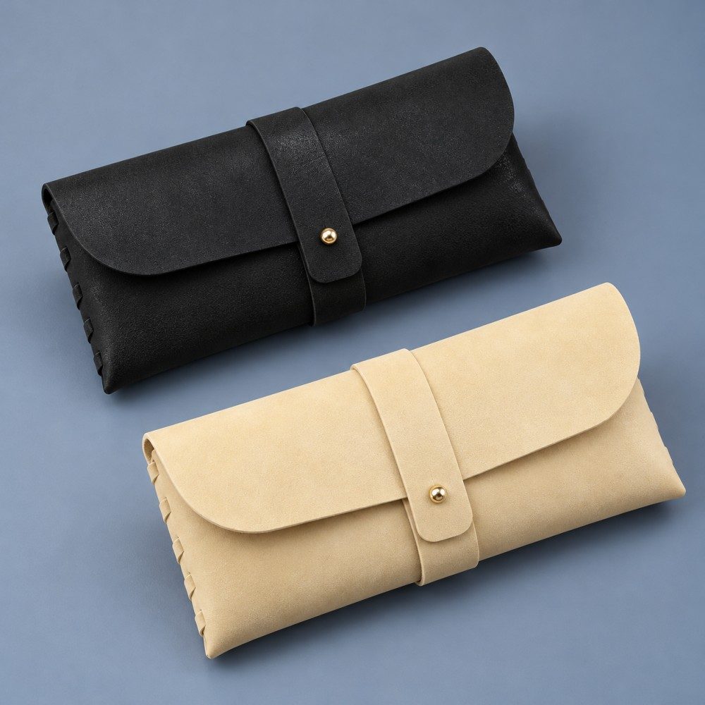 Black and pale yellow soft eyeglass cases with matching envelope shapes and gold-tone stud fastenings.