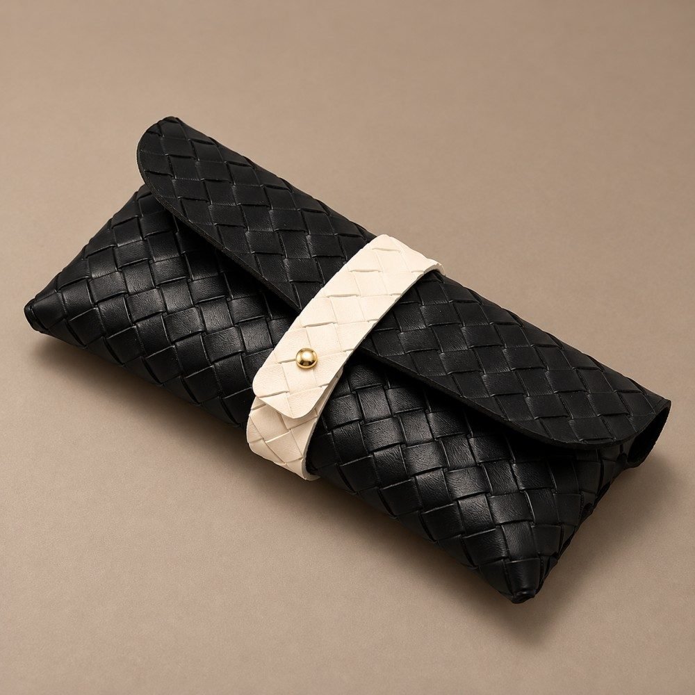 Close-up of black woven eyewear pouch with central strap and gold-tone stud