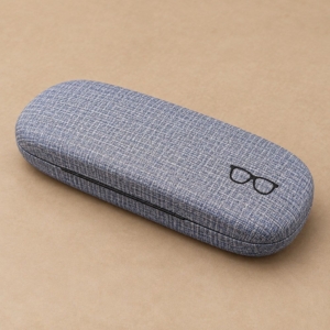 Blue-gray glasses case with a linen-look PU covering and black eyeglasses graphic on a warm beige background.