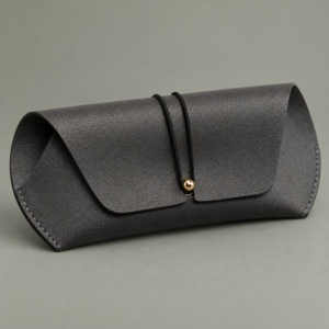 Gray cord-and-stud case from the soft sunglasses cases wholesale range on a muted sage background.