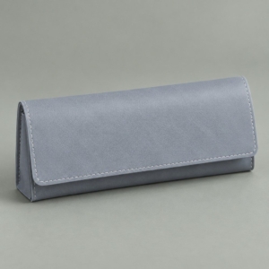 Blue-gray soft eyeglass case with a broad rectangular flap and light edge stitching on a muted sage-gray background.