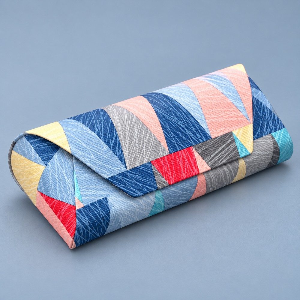 Closed magnetic glasses case with a blue and pink geometric PU exterior and rounded end panel on a blue-gray background.