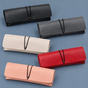 Five PVC faux leather eyeglass cases in black, gray, ivory, red and peach with matching black elastic closures.