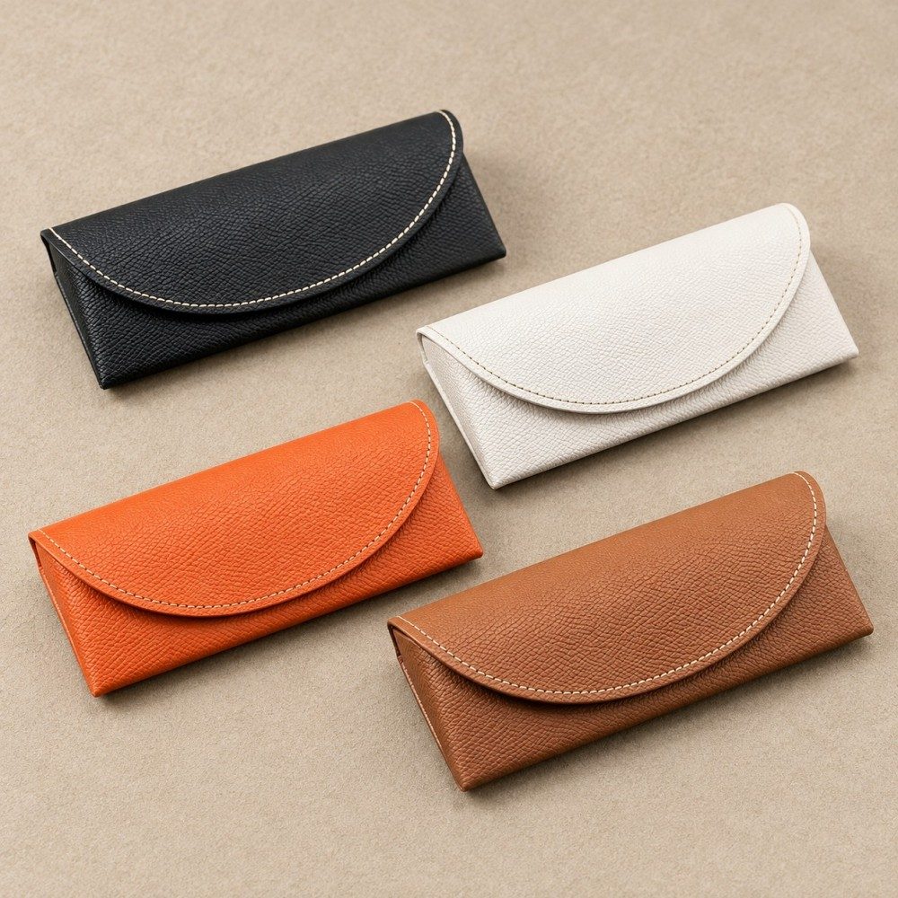 Close-up of lychee-grain PVC faux leather and cream stitching on a brown glasses case