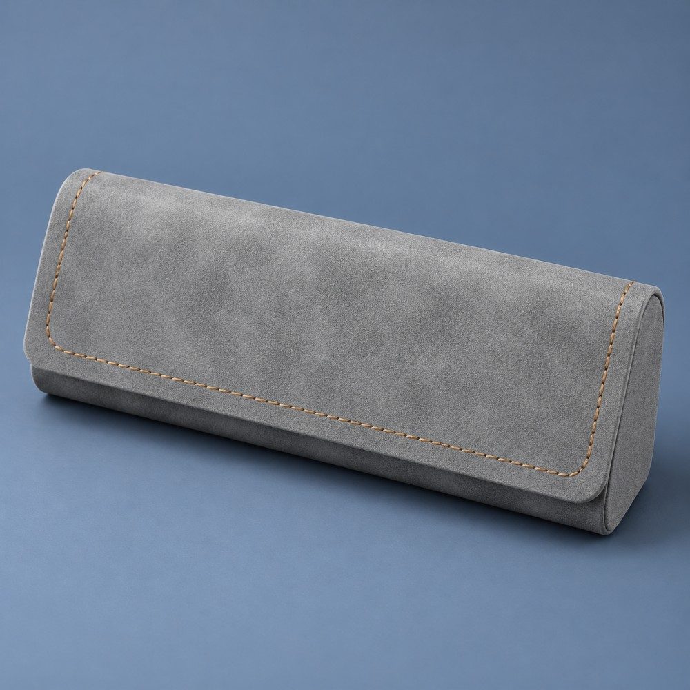 Gray JH PU eyeglass case with tan contrast stitching and a closed magnetic flap on a slate blue background.