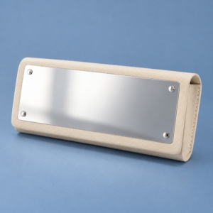 Ivory PVC glasses case with a rectangular stainless steel mirror and four corner fasteners on a muted blue background.