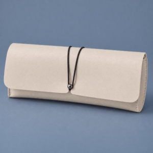 Ivory PVC case from the soft eyeglass cases wholesale range, with a black elastic loop and dark metal stud.