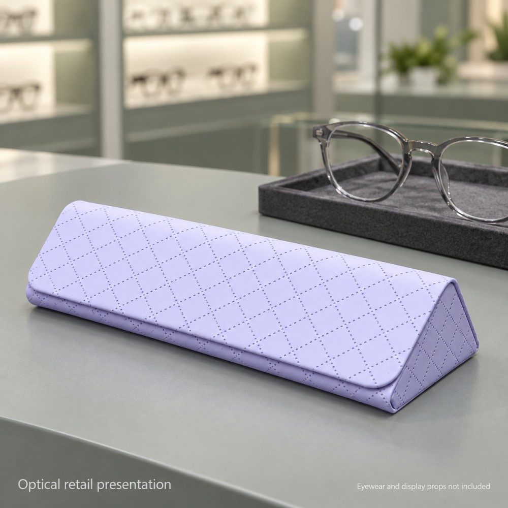 Lavender diamond-pattern glasses case on an optical store counter beside eyeglasses on a display tray.