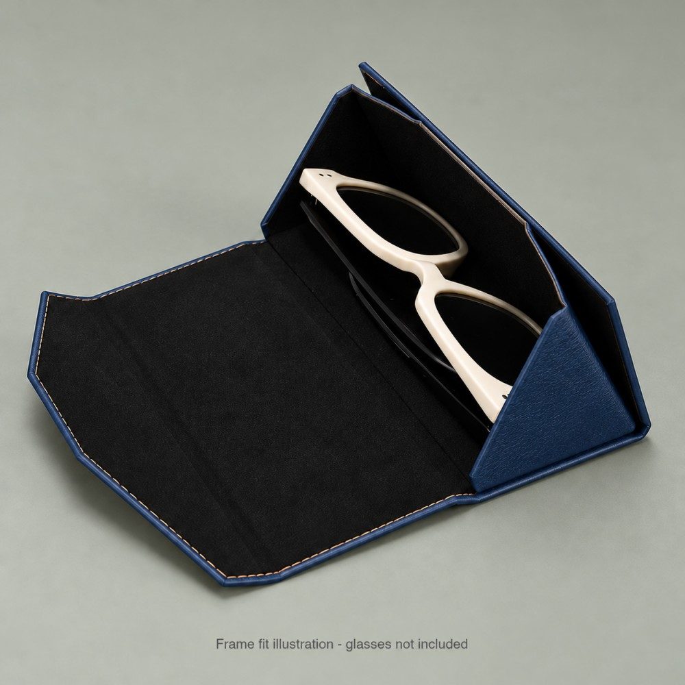 Open navy foldable glasses case with black lining and cream-framed sunglasses illustrating eyewear placement.