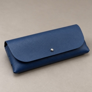 Navy soft eyeglass case inside a kraft box beside a grey cleaning cloth, shown as an optional packaging concept with accessories excluded.