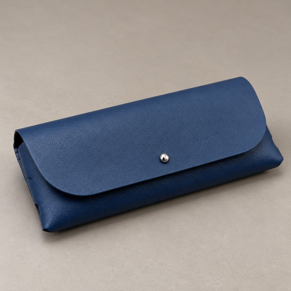 Navy soft eyeglass case inside a kraft box beside a grey cleaning cloth, shown as an optional packaging concept with accessories excluded.