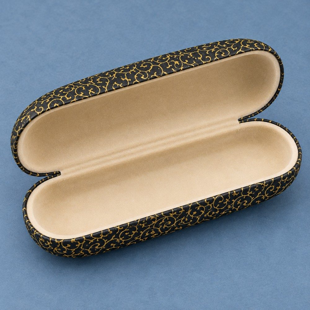 Open black and gold eyeglass case showing beige velvet lining inside the rounded lid and base.