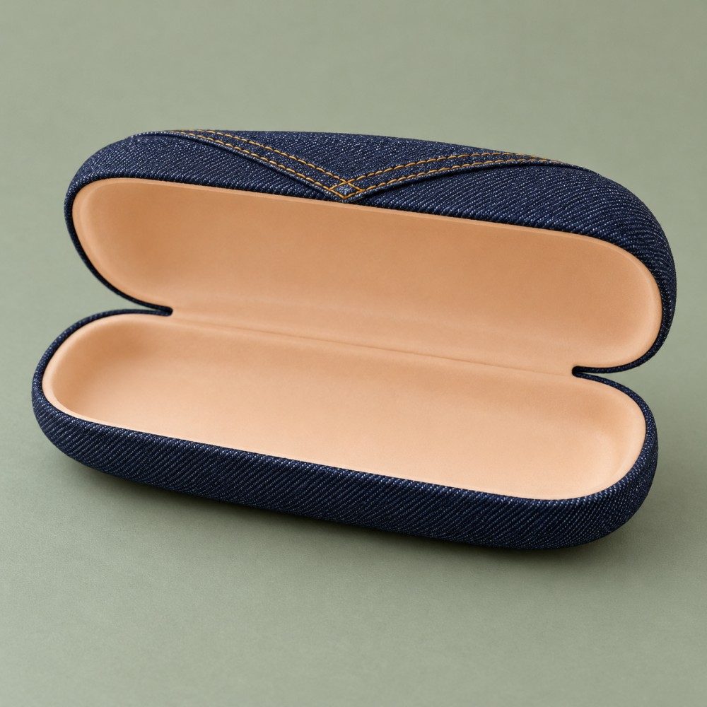 Open indigo hard glasses case showing pale apricot lining inside the rounded lid and base.
