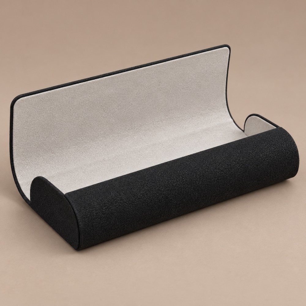 Open black flap-top glasses case showing a light-colored lining, curved front wall and undivided interior.