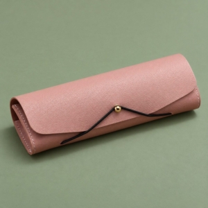 Pink glasses case with a pebbled surface, black elastic cord and gold-tone stud