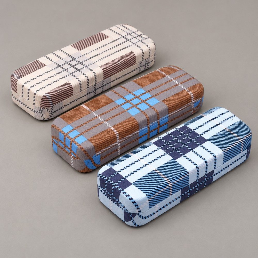 Three plaid metal eyeglass cases in cream and brown, brown with blue accents, and blue and navy.