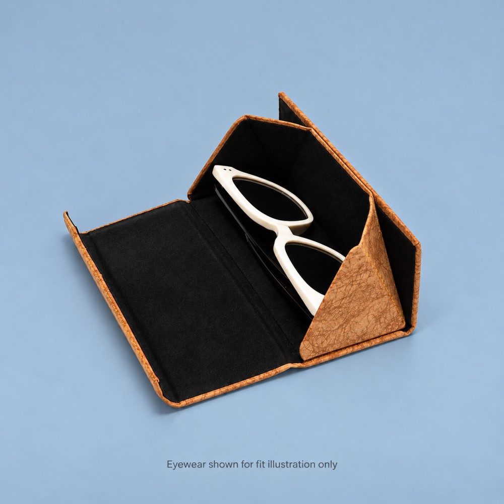 Open coffee brown glasses case showing black lining, folding side panels and white cat-eye sunglasses placed inside.